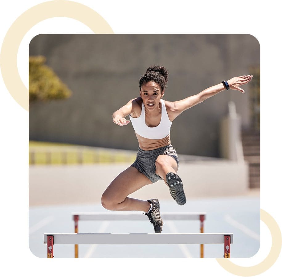 Athlete jumping over hurdle on track.