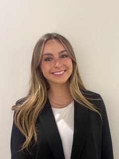 Smiling young woman with blonde hair in a black blazer.