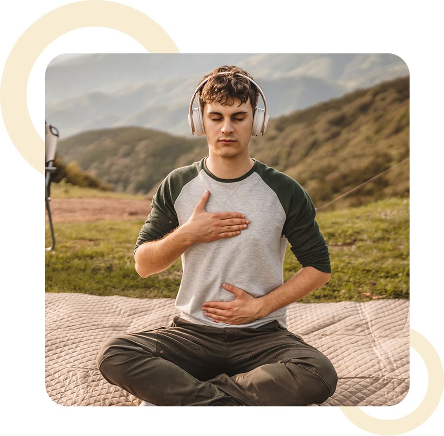 Man meditating outdoors with headphones on.