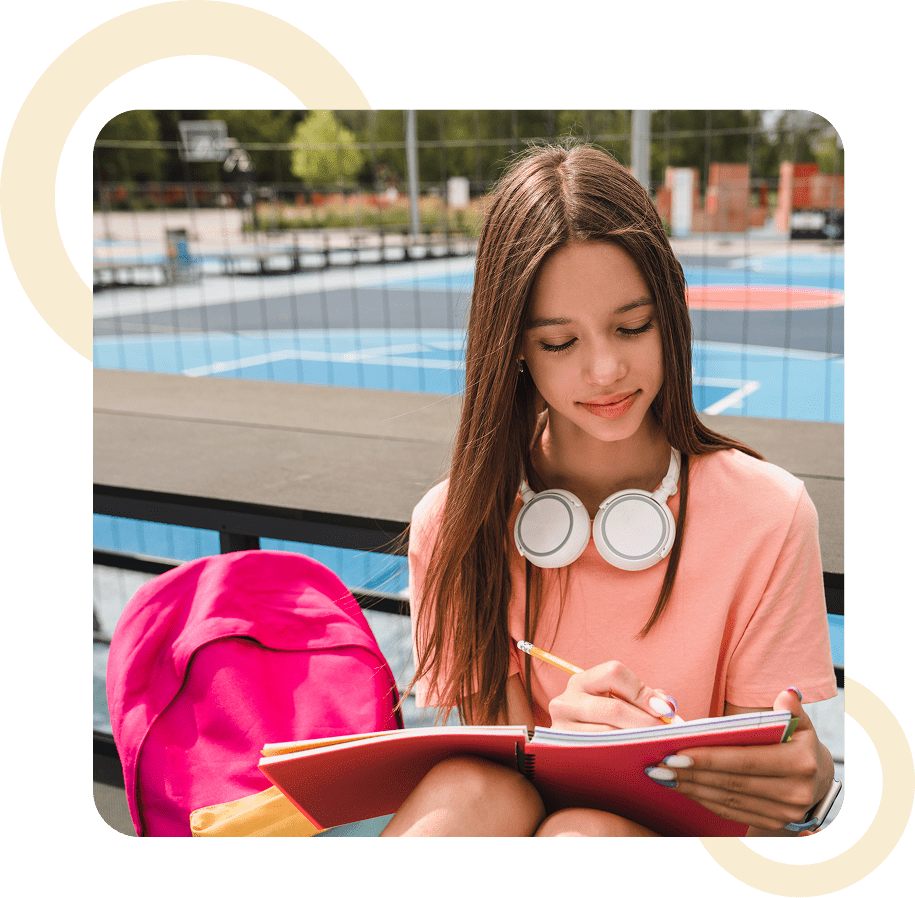 Girl writing in notebook at basketball court.