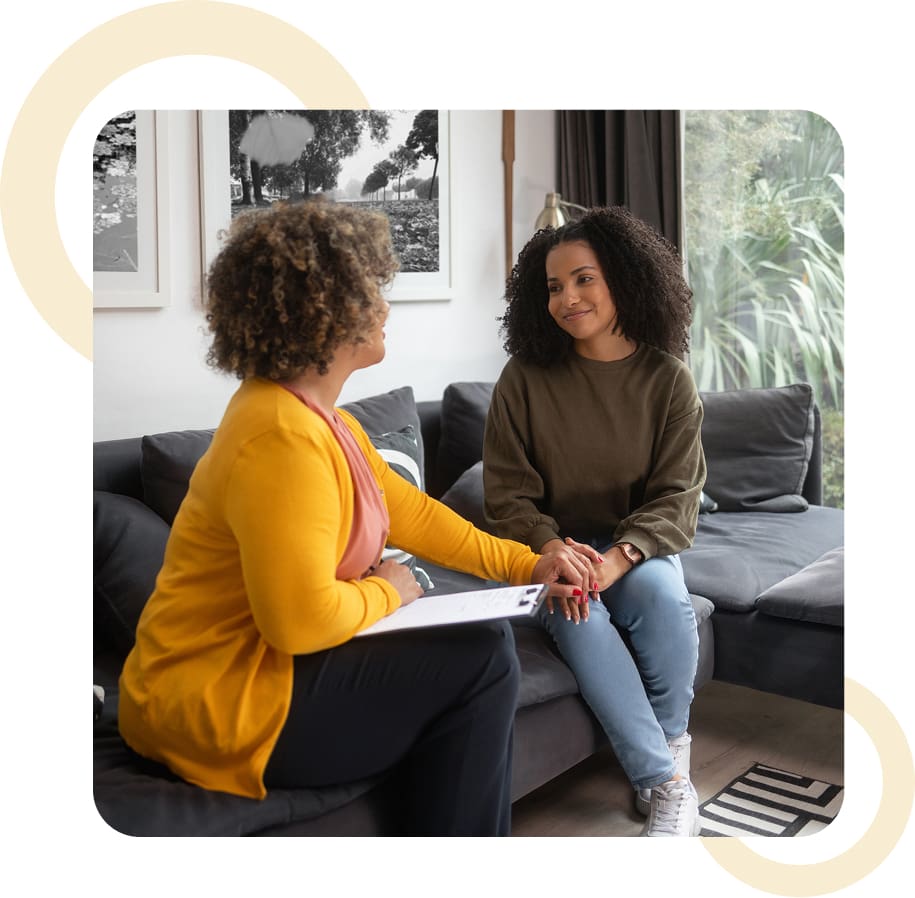 Two people talking on a couch, smiling.