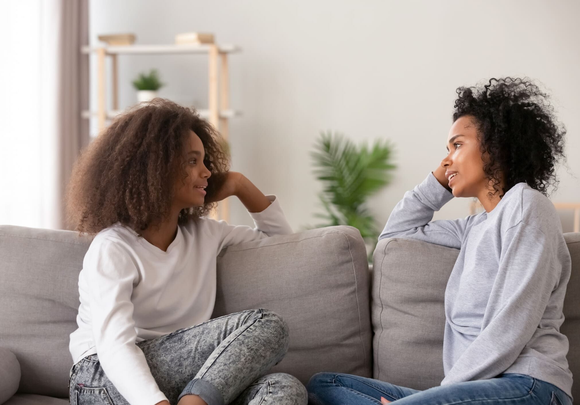 Two people talking on a gray sofa.