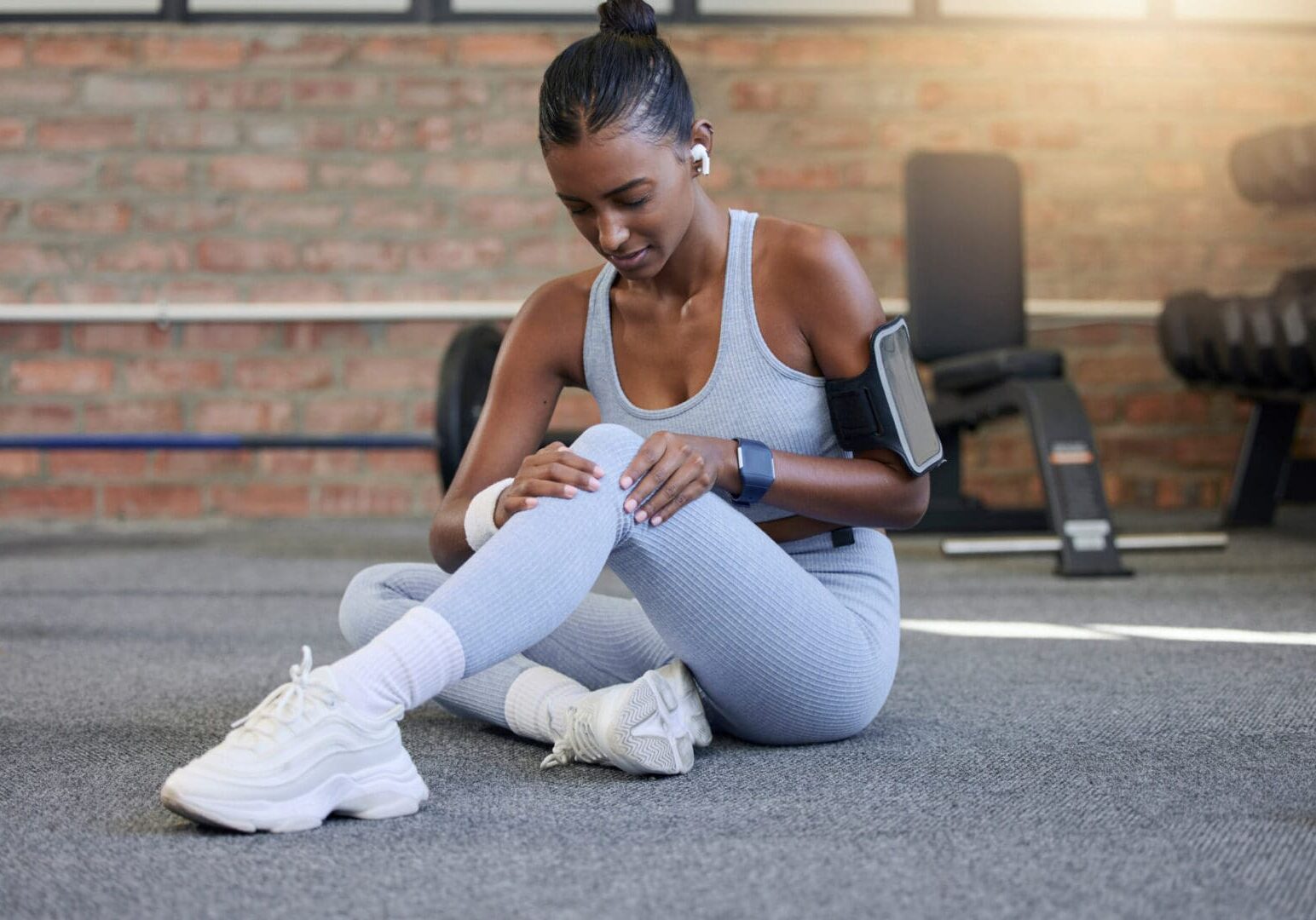 Woman in gym outfit sitting on floor.