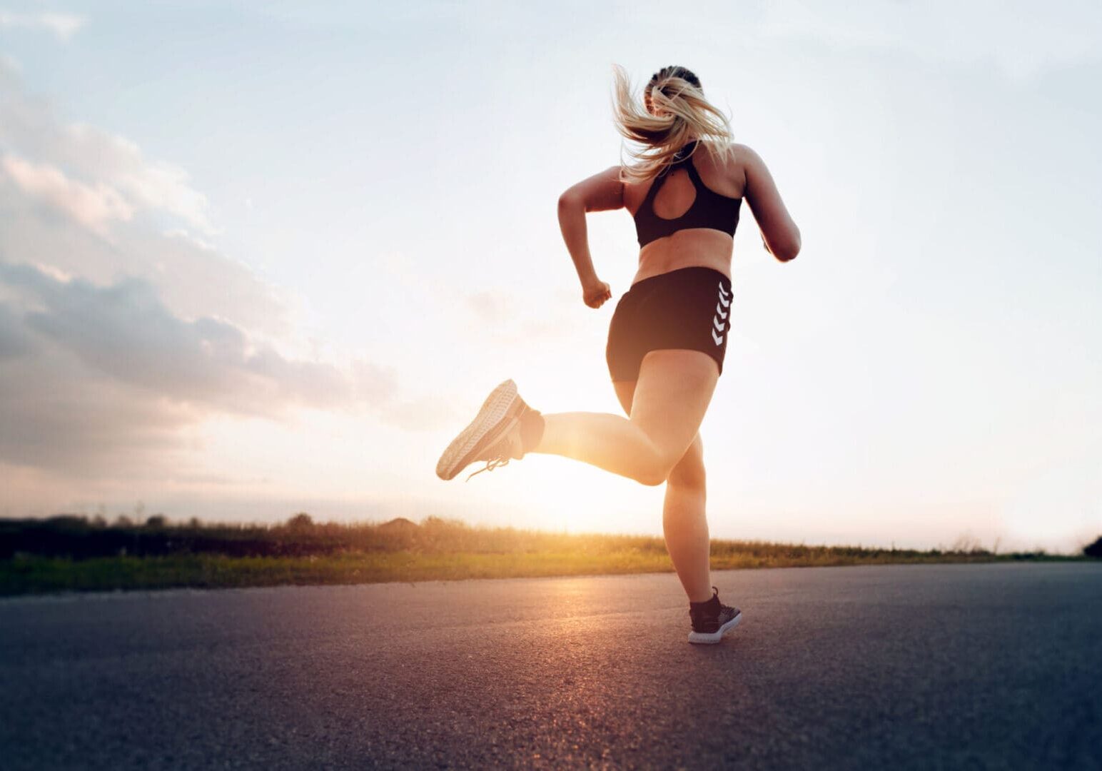 Woman running on road during sunset.