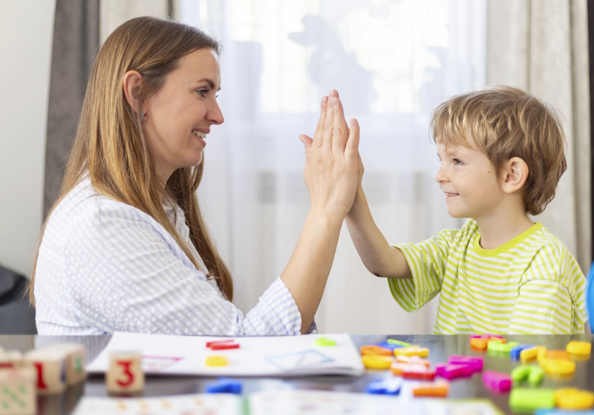 Woman and child high-fiving during playtime.