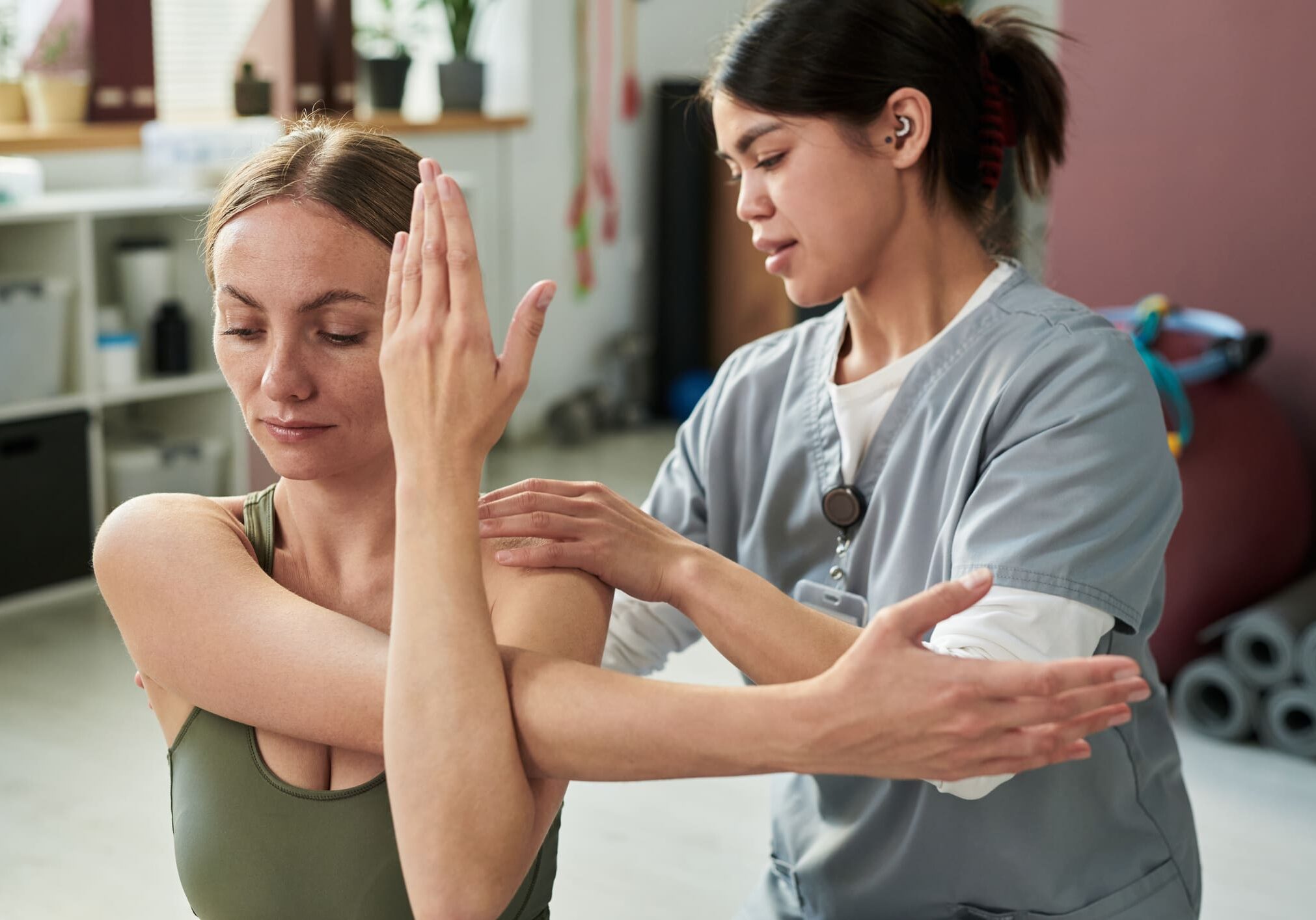 Physical therapist assisting woman with arm stretch.