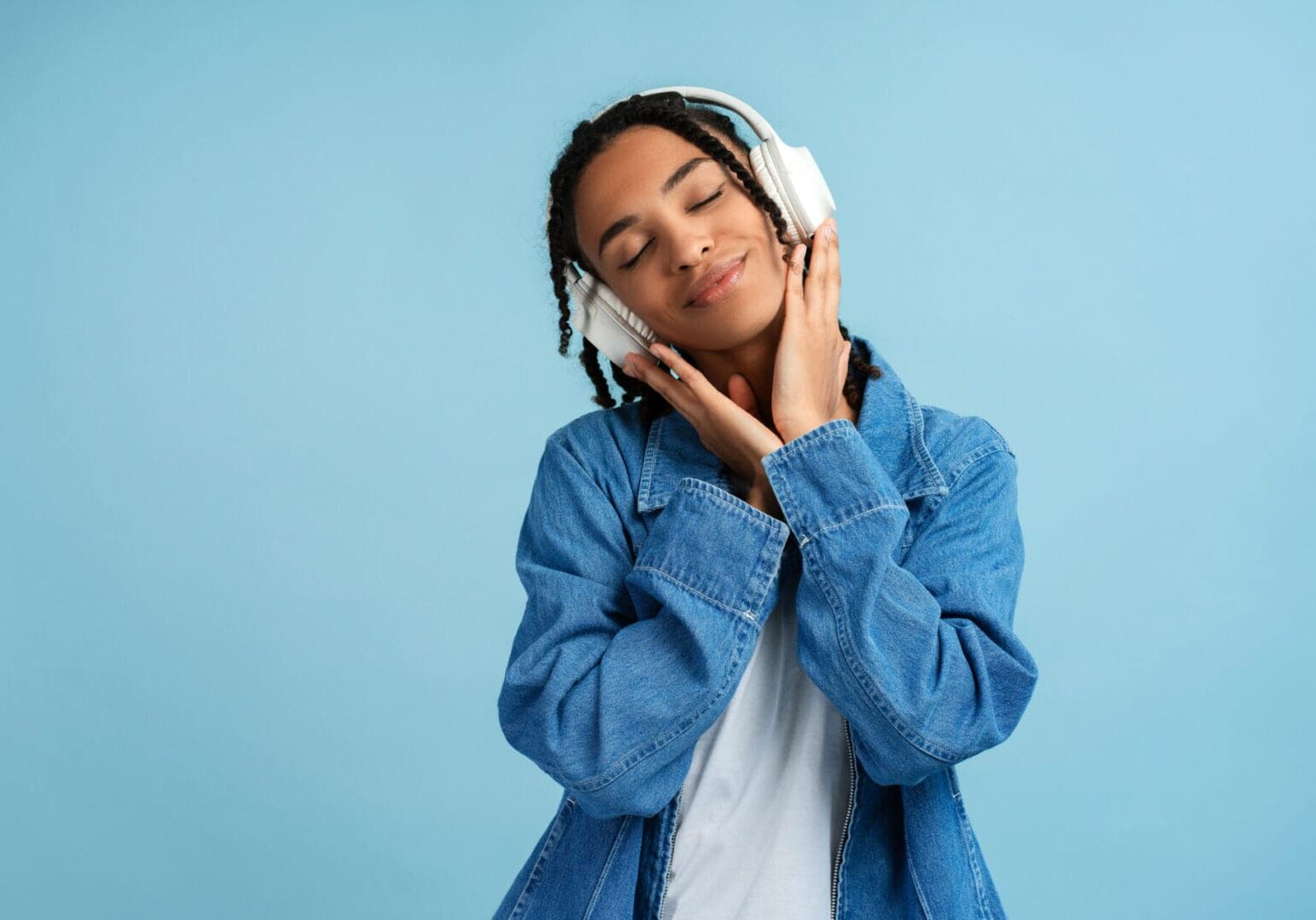 Person enjoying music with headphones, blue background.