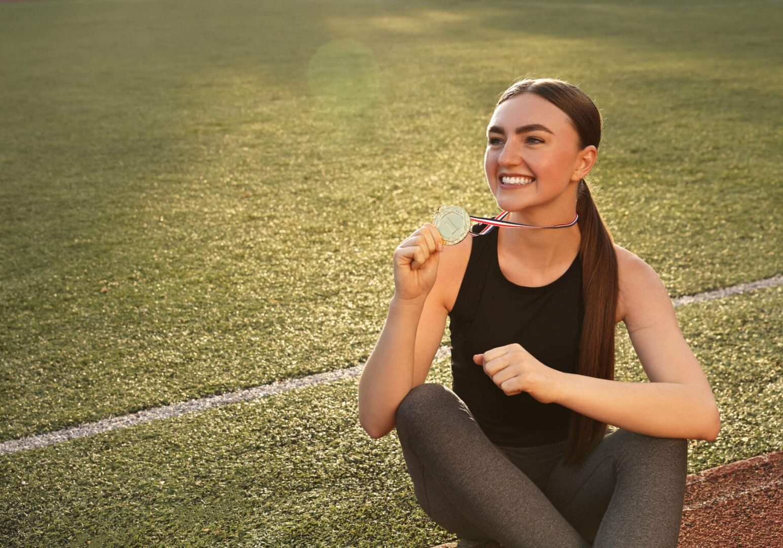 Athlete sitting on field with medal.