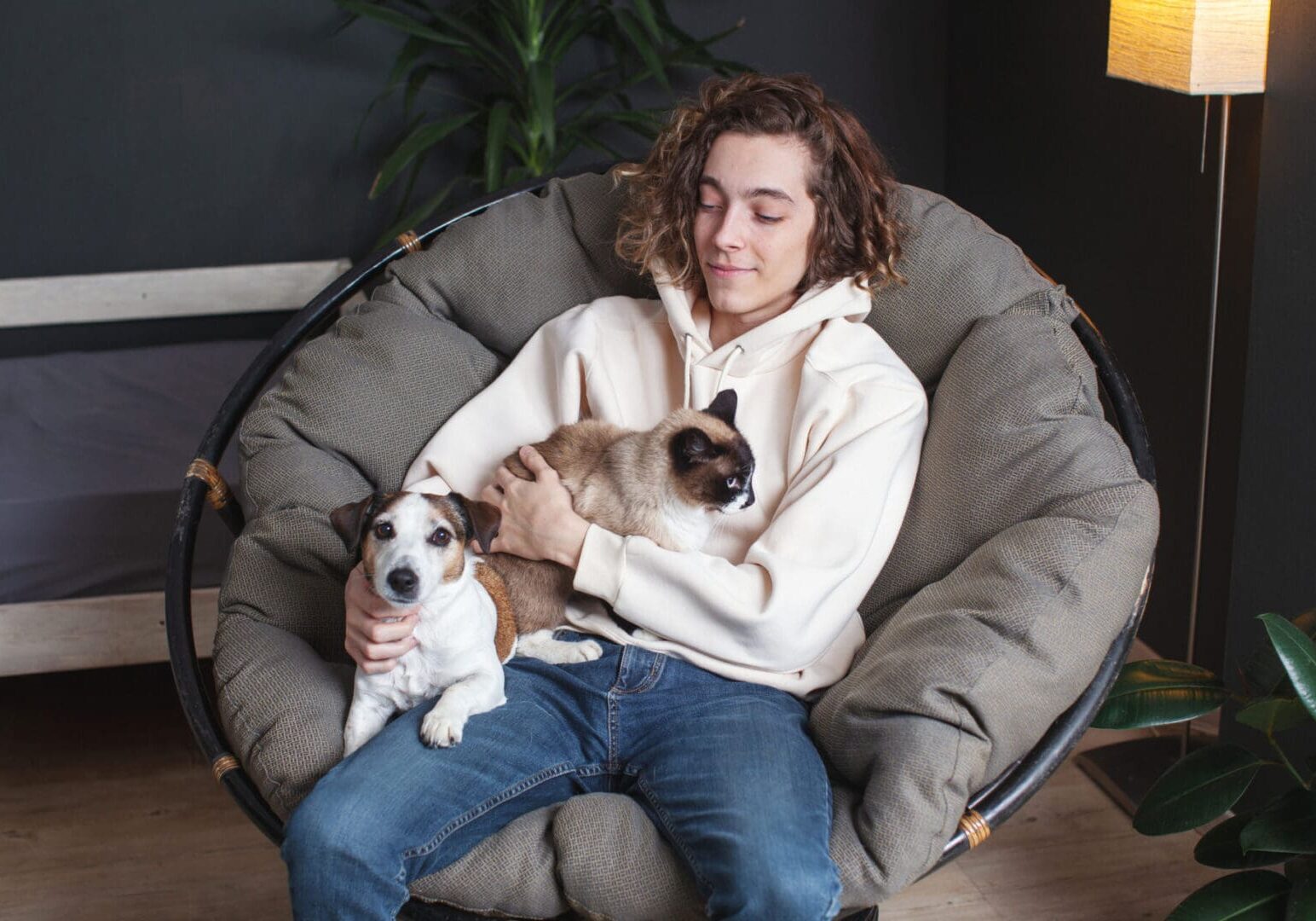 Person holding cat and dog in chair.